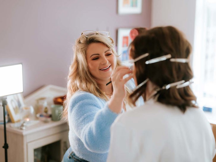 makeup artist doing makeup with bride facing towards her